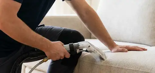Professional upholstery cleaner deep-cleaning a fabric sofa with a handheld extraction tool, Hollywood, FL.
